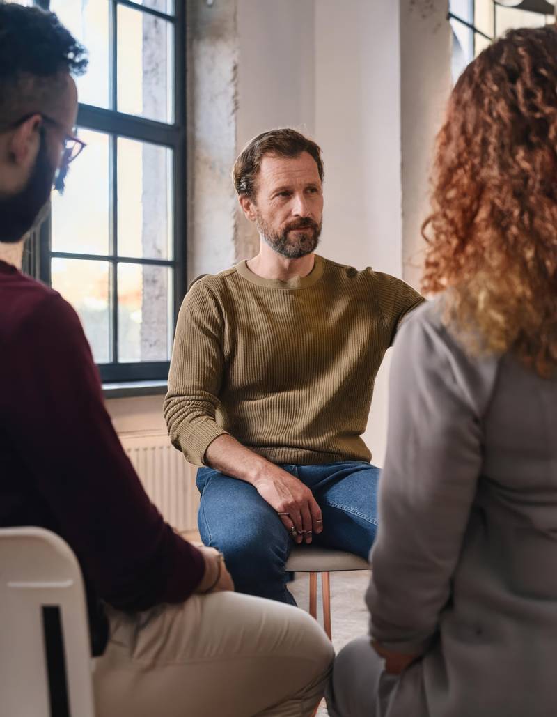 An addiction treatment group therapy session focussing on a man in the group