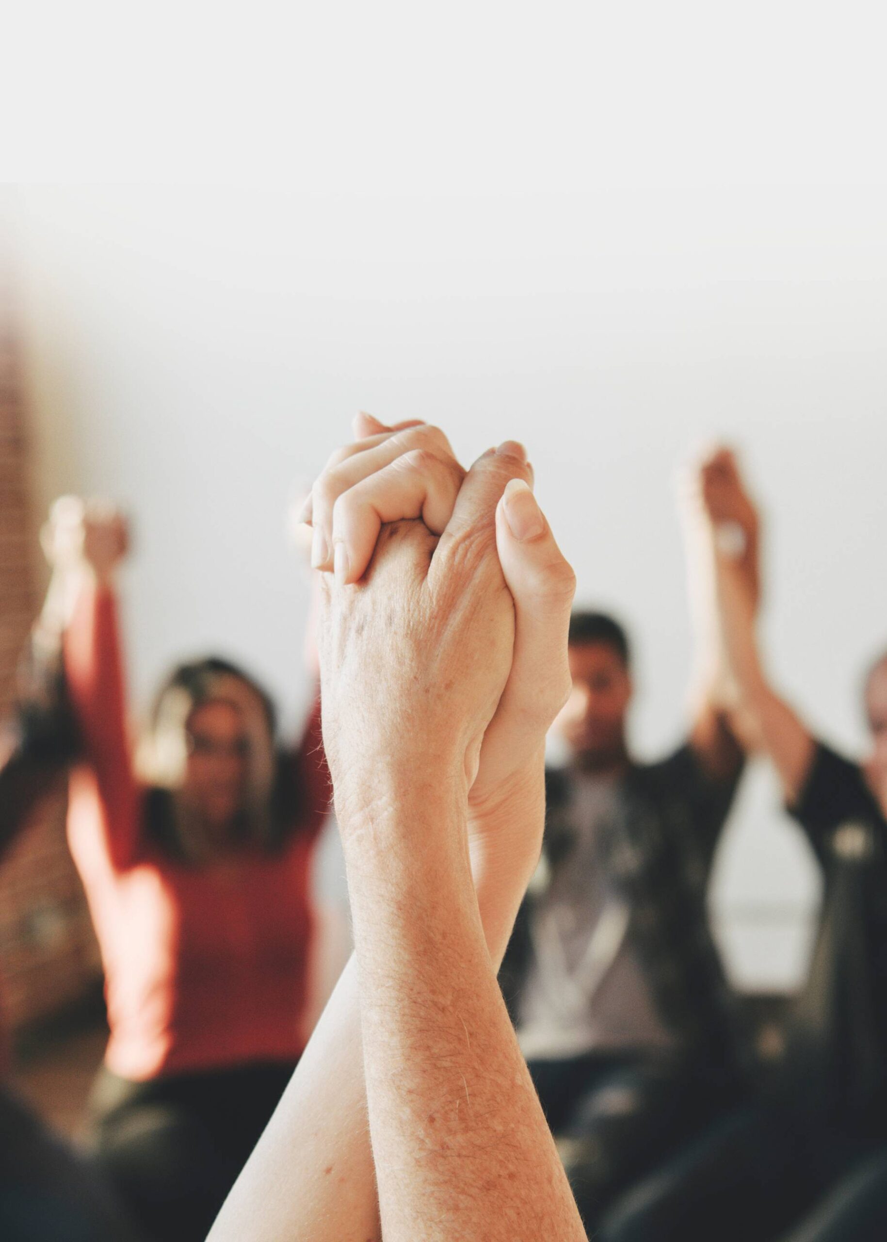 An addiction treatment group session with all holding hands above their head while seated in a circle