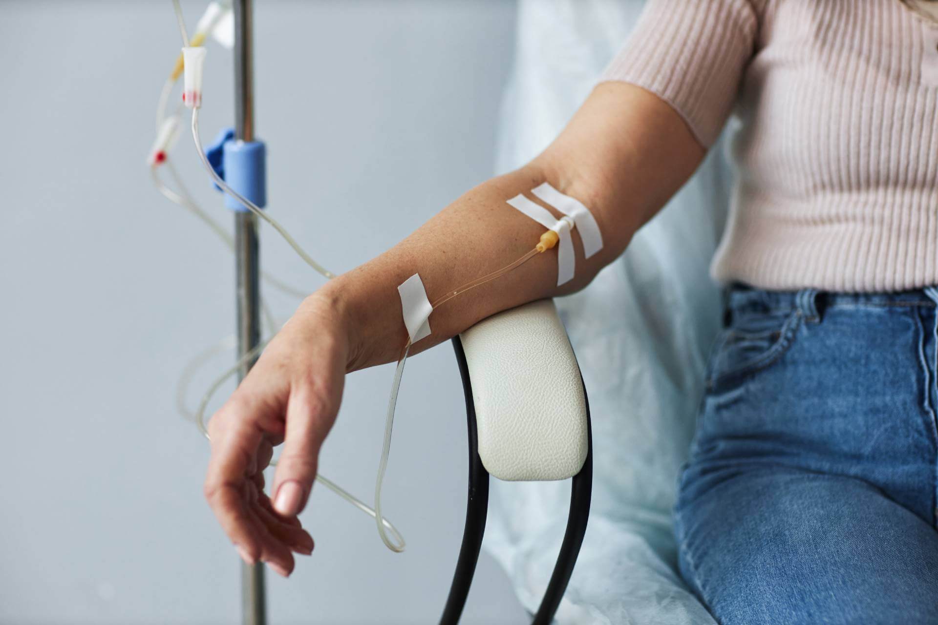 An IV in the arm of a woman sitting in a chair.